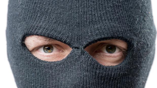 A close-up of a man wearing a balaclava looking straight into the camera